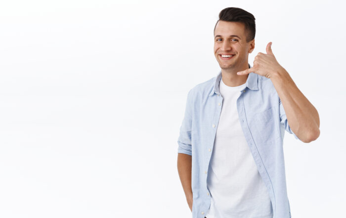 Give me call. Portrait of handsome stylish adult man showing phone sign near face and smiling as promoting his service, give contact number in case you need talk, standing white background.